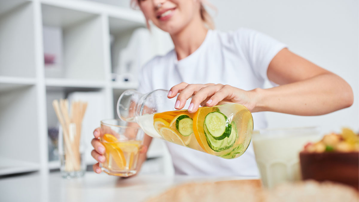 Mulher a servir água aromatizada com pepino e citrinos